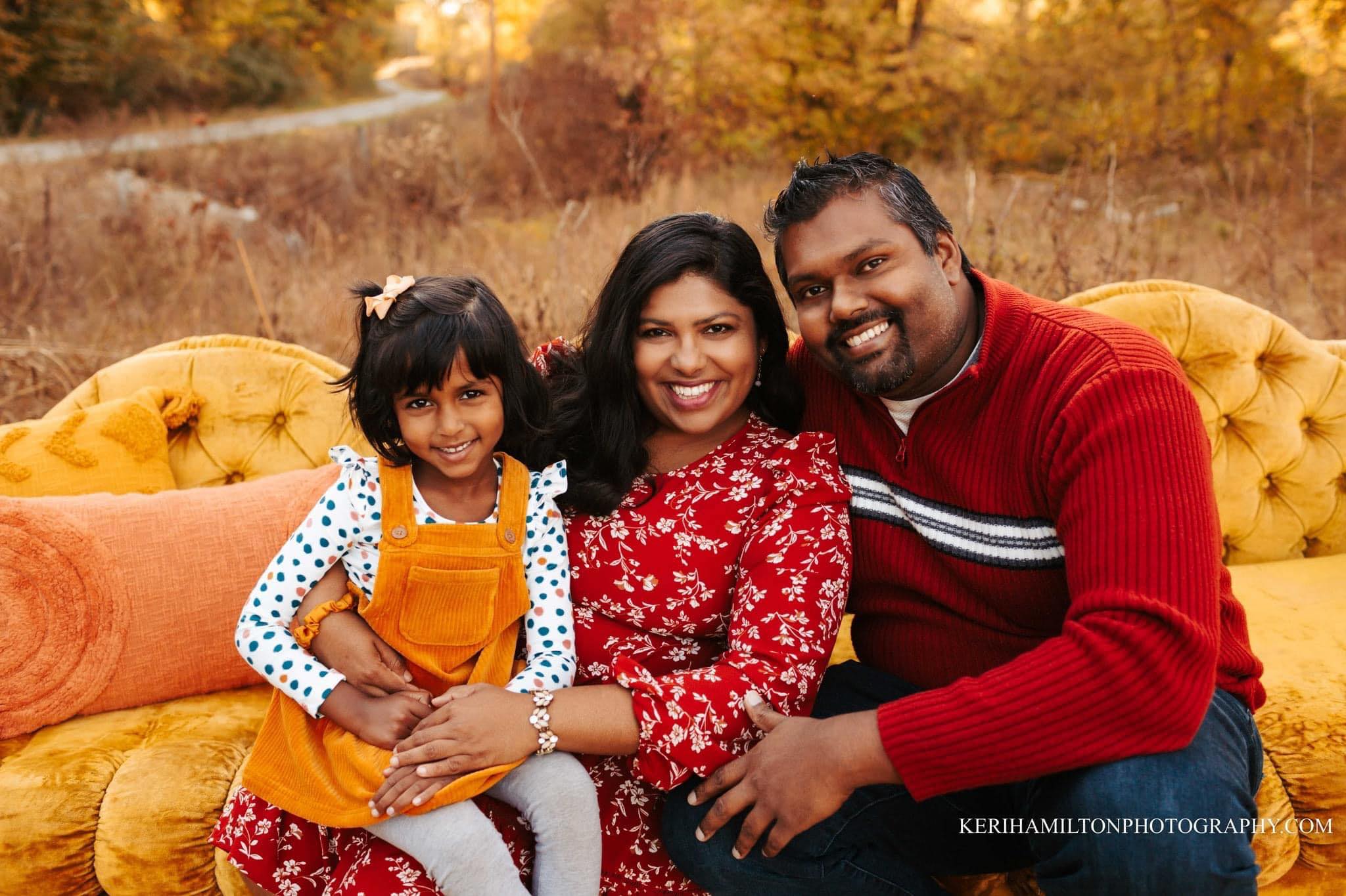 Harshi Perera smiles alongside her husband and daughter