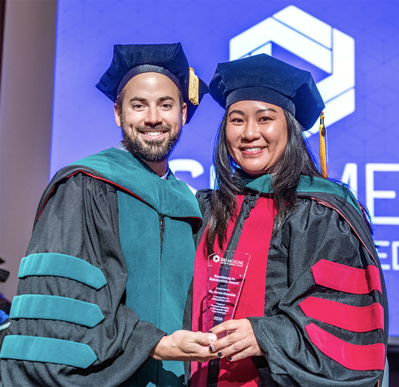Image of Dr. Jacob Ribbing and Dr. Annie Kowalis as she receives an award at the 2024 SIU DMSc Hooding Ceremony