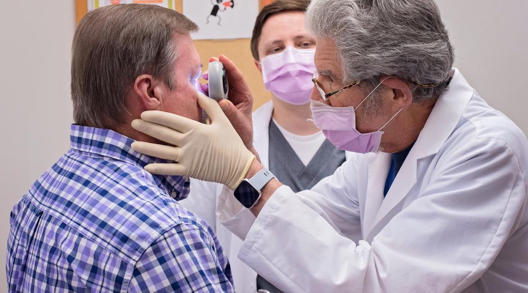 Dermatologist checks on a mole near a patients eye