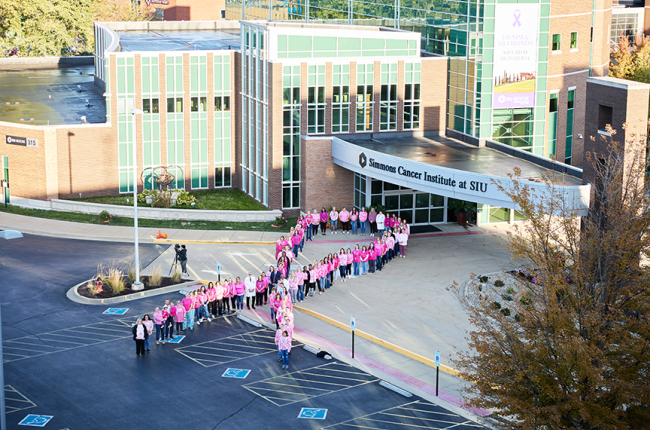 Simmons Cancer Institute pink ribbon of people in parking lot