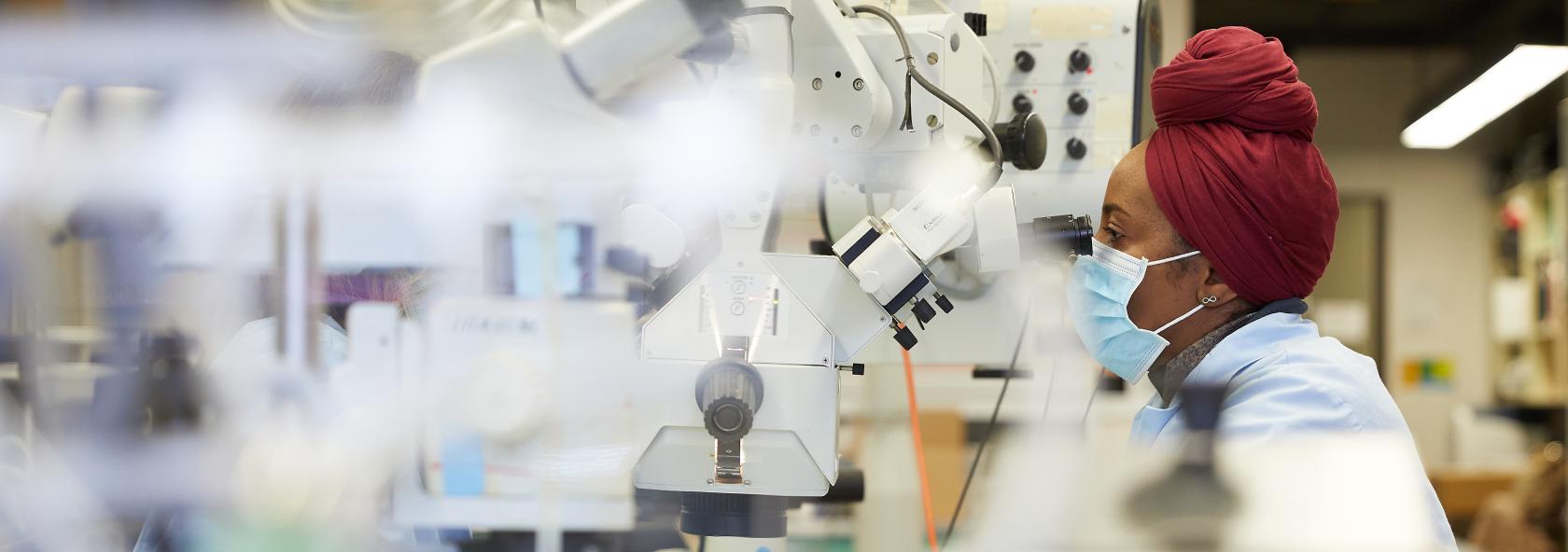 Medical student looks under microscope in a research lab