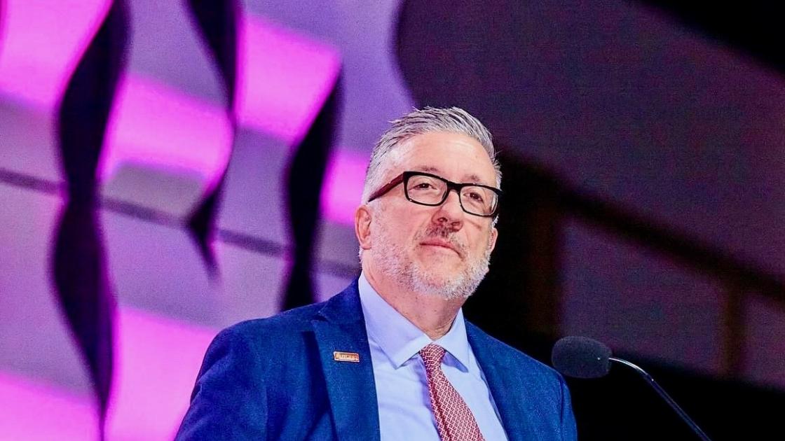 Matt McQuillan, DMSc, PA-C, DFAAPA stands at a podium on stage during a conference presentation