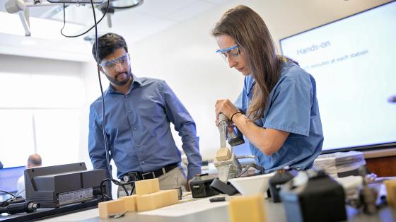 Two people wearing safety glasses at a workbench