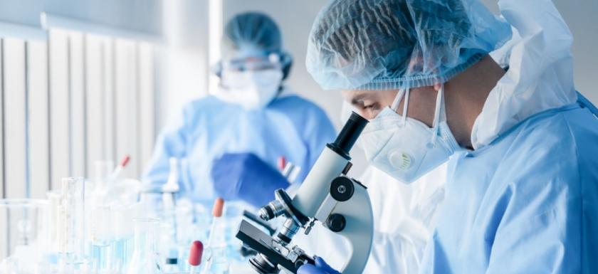 Scientist looking into microscope. 