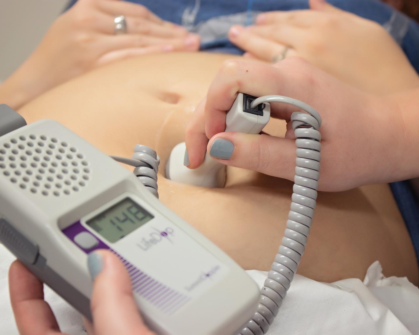 Nurse using a heartbeat doppler on a woman's belly