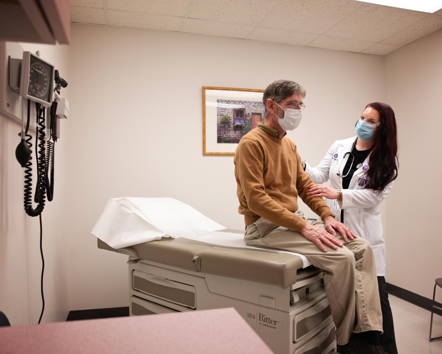 Man sits on an examination table during an physical exam