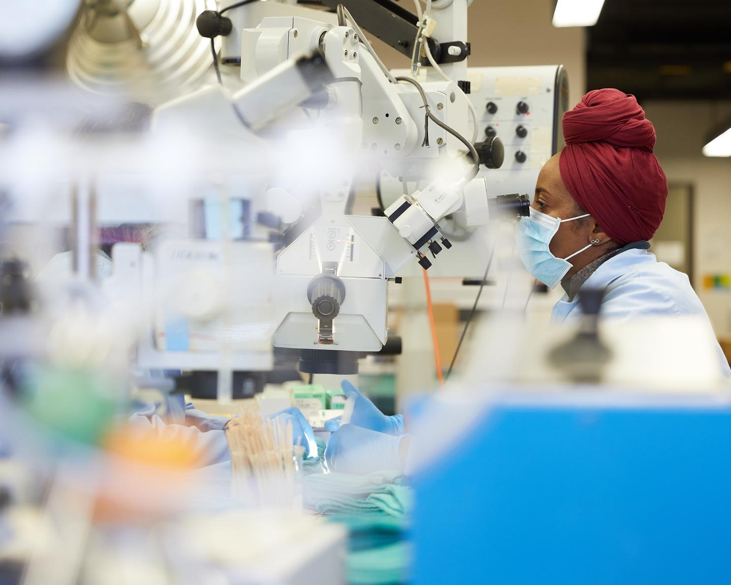 Medical student looks under microscope in a research lab