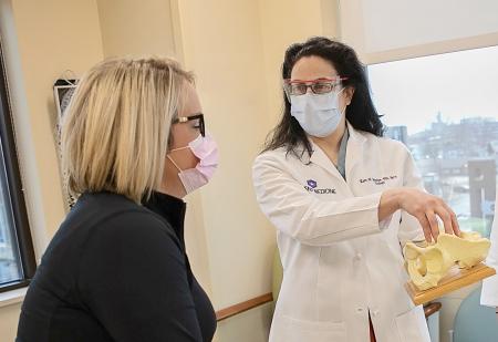 Doctor uses a partial skeletal model while talking to a patient