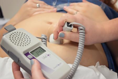 Nurse using a heartbeat doppler on a woman's belly
