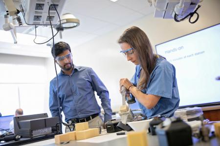 Two people wearing safety glasses at a workbench