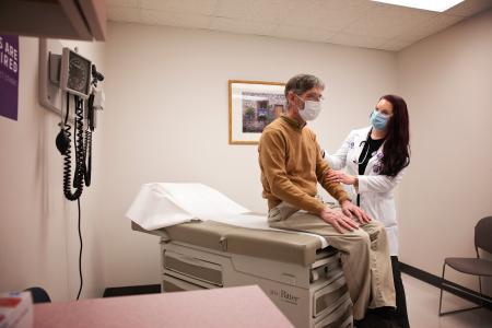 Man sits on an examination table during an physical exam