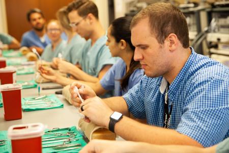 Students sitting at a table with surgical tools