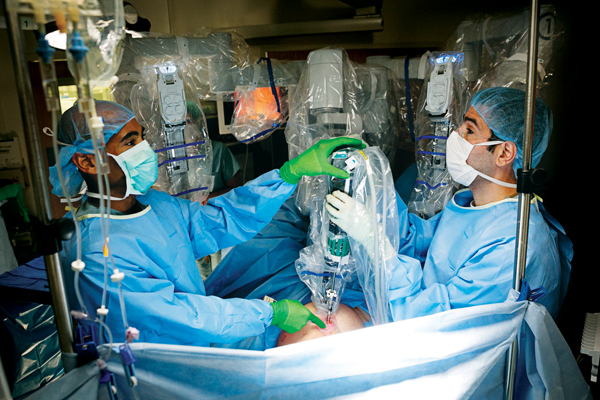 Former OB-GYN fellow Tatnai Burnett, MD, and Assaad Semaan, MD, prepare the robot and lock its arms in place before using the console.